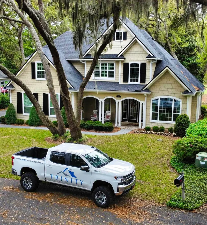 Trinity Restoration & Roofing truck in front of a finished roof