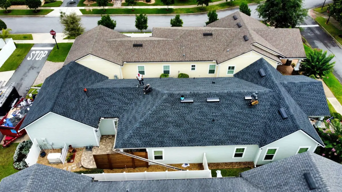 Aerial view of a completed roof replacement with crews finishing cleanup