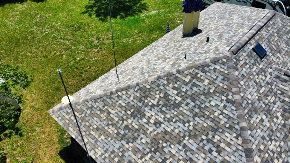 Aerial view of a finished gray shingle roof with a chimney
