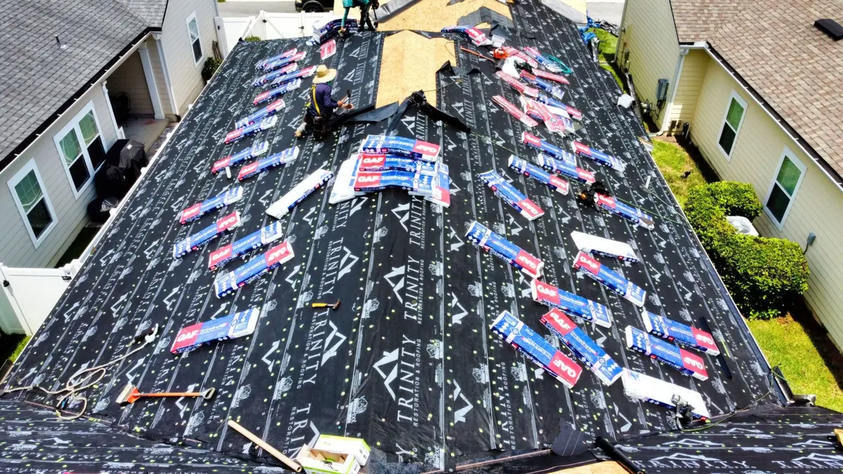 Trinity crew laying new underlayment and shingle bundles on a roof